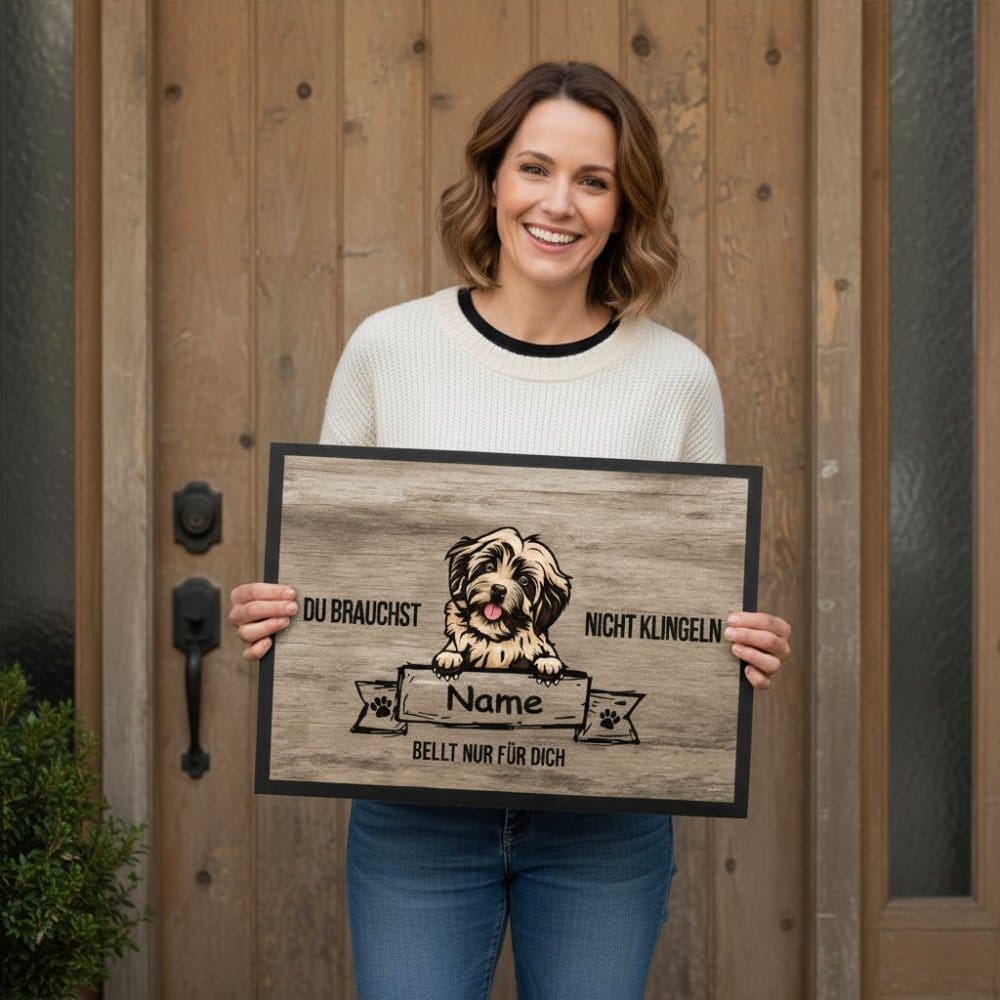 Frau steht vor  Haustür und hält eine Fußmatte in den Händen. Auf der Matte steht: Du brauchst nicht klingeln ...bellt für Dich