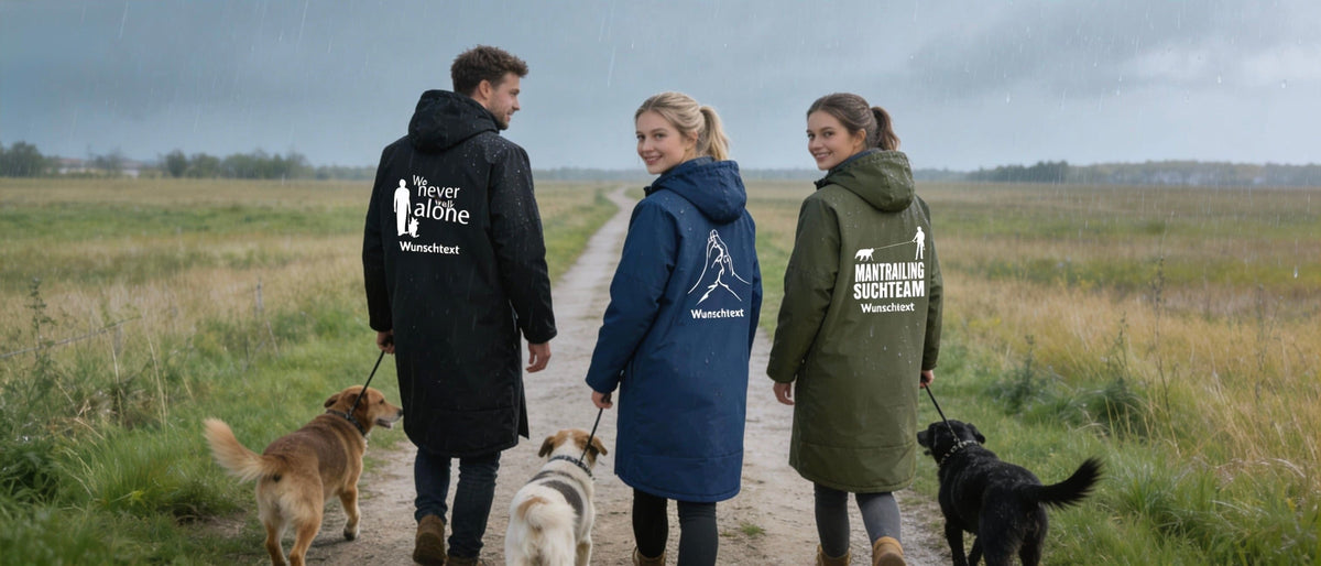 Gruppe geht mit Outdoor-Mantel und Hunden spazieren im Regen