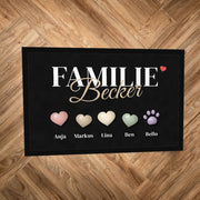 Fußmatte „Familie Becker“ mit farbigen Herzen, einer Pfote und Namen darunter, auf Parkettboden