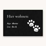 Fußmatte „Hier wohnen“ mit Familiennamen und zwei weißen Pfoten mit Hundenamen, Mattenfarbe Schwarz
