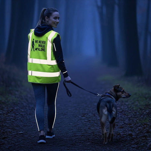 Frau spaziert mit Hund und gelber Warnweste in der Dämmerung