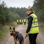 Eine Frau mit Schäferhund und einer Mantrailinggruppe in gelben Warnwesten