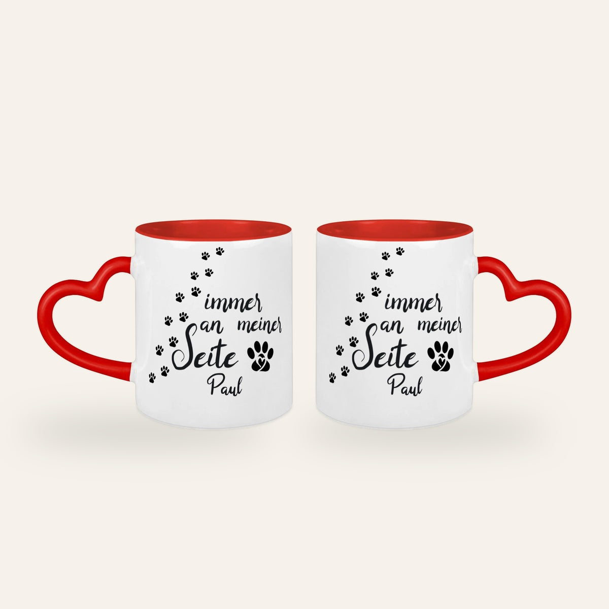 Weiße Tasse mit rotem Herzhenkel, dem Spruch Immer an meiner Seite, Pfotenspuren und dem Namen Paul, Ansicht beider Seiten