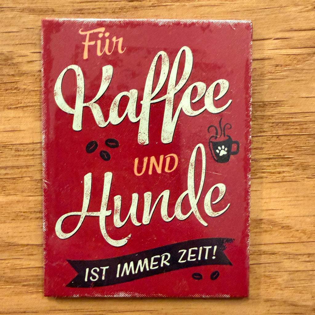 Roter Retro-Magnet mit dem Spruch „Für Kaffee und Hunde ist immer Zeit!“, Kaffeetasse mit Pfote und Kaffeebohnen, auf Holz